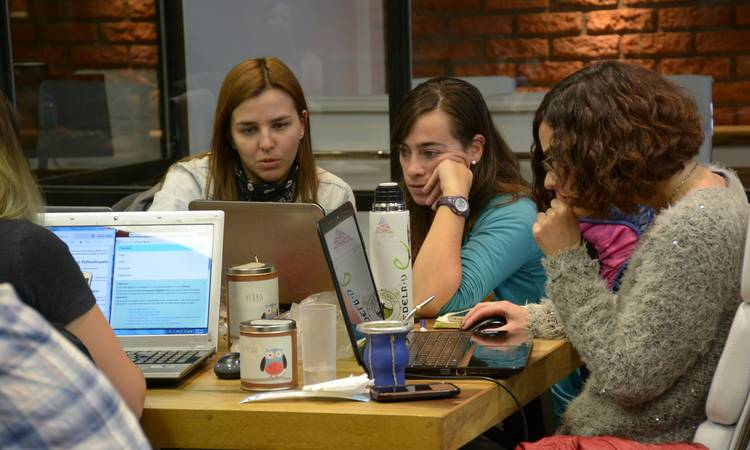 A group of people using laptops and assistive devices to read emails in a modern workspace