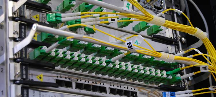A close-up of network cables and a monitor displaying encrypted code, representing secure API data transmission