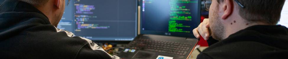 A team of developers collaborating on API security in a modern workspace, code and network diagrams visible