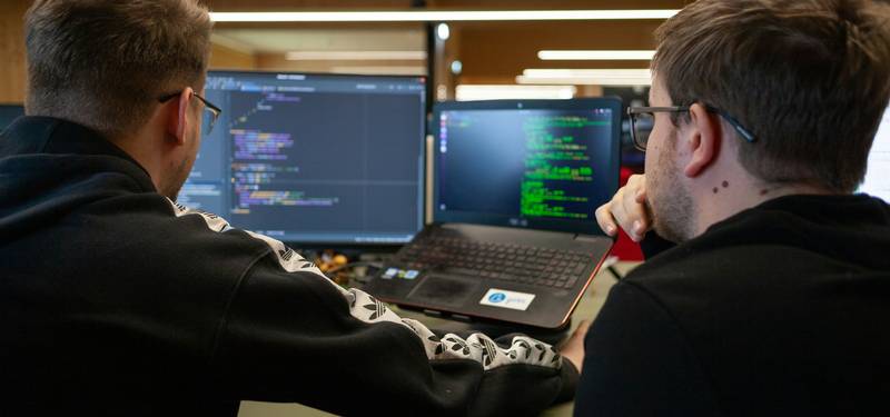 A group of programmers collaborating at computers with code displayed—illustrating real-world coding and naming conventions