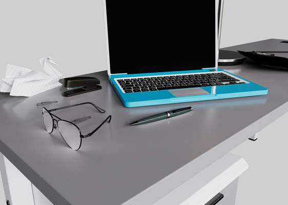 A close-up photo of a designer's desk with a laptop, color swatches, and an open image editing program