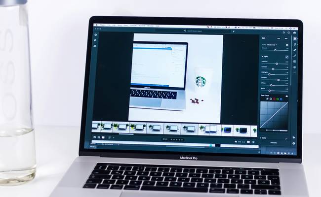 A designer compressing images for website speed and SEO—monitor, laptop, digital workspace