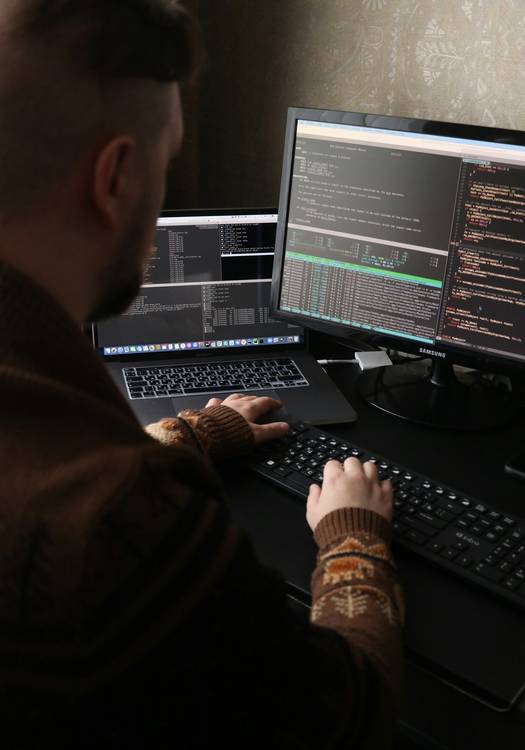 A developer at a workstation reviewing obfuscated JavaScript code for production security
