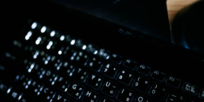 A close-up of cryptography hardware and a programmer working on a laptop, representing hashing and cybersecurity