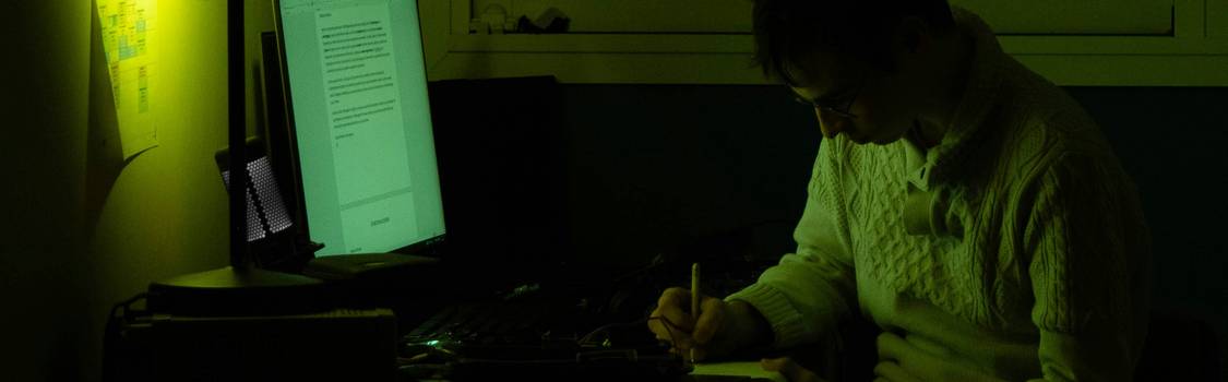 A person working on a laptop, surrounded by spreadsheets and code, building web tables
