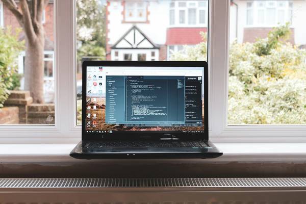 A modern workspace showing a developer using multiple utility tools on a laptop, surrounded by notepads and code on the screen