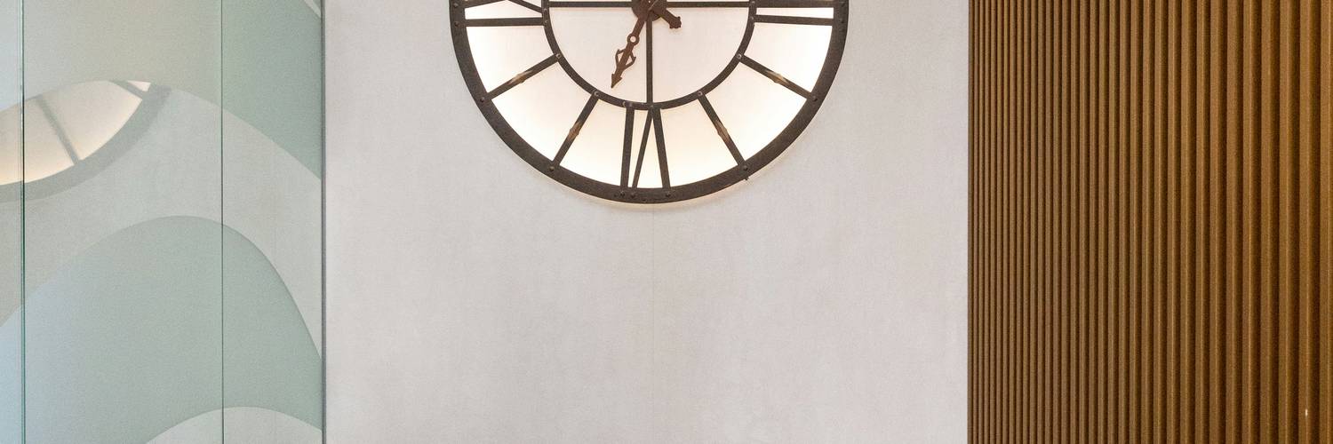 A bright, modern office wall with clocks showing times in multiple international cities, representing global time zone conversion